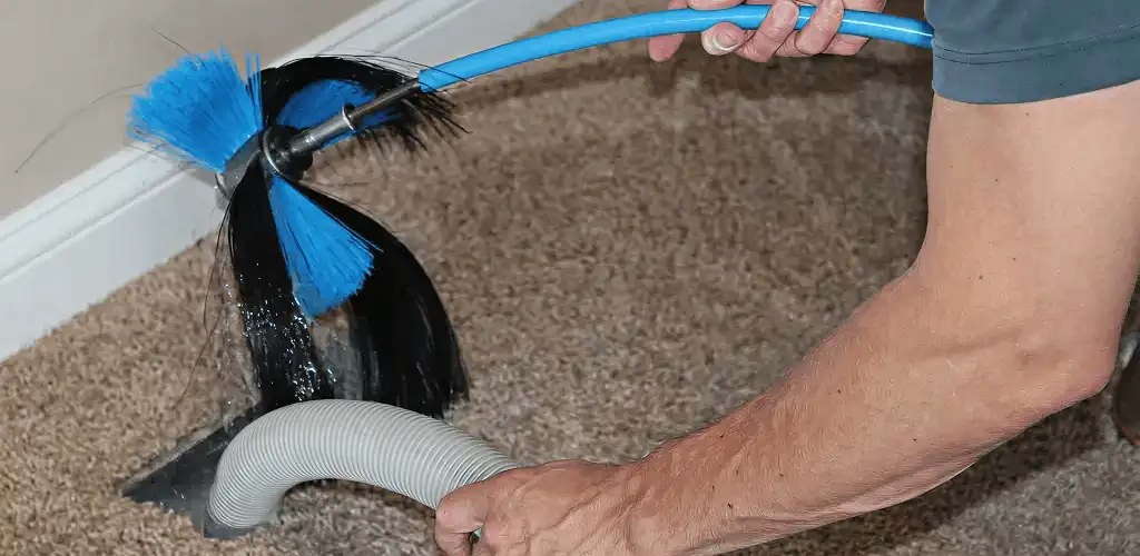 Dryer vent cleaning technician brushing lint from a vent line in Detroit, MI