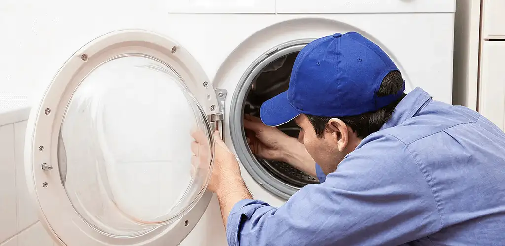 Washing machine repair handyman inspecting a front-load washer drum in Detroit, MI