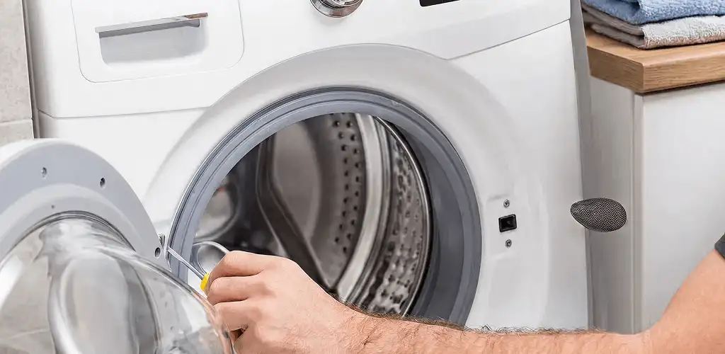 Handyman repairing a front-load washing machine and inspecting the drum in Detroit, MI